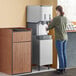 A woman using a Scotsman Meridian ice and water dispenser to fill a drink.