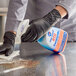 A person in black gloves using KIK Pure Bright All Purpose Germicidal Cleaner to clean a counter.