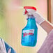 A bottle of SC Johnson Windex Glass & More cleaner being sprayed onto a glass surface.