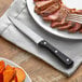 A plate with a steak and a Choice jumbo steak knife on a table.