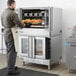 A man standing in front of a Main Street Equipment double deck commercial convection oven in a school kitchen.