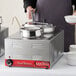 A man using a Choice stainless steel steam table adapter plate to hold bowls of food.