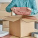 A man opening a box with a stack of Lavex pink void fill paper.