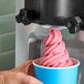 A close up of a person's hand holding a cup of pink DOLE SOFT SERVE ice cream.