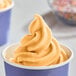A close up of a cup of DOLE SOFT SERVE orange soft serve ice cream.