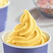 A bowl of yellow DOLE Mango soft serve with sprinkles.