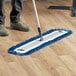 A person using a Lavex microfiber mop to clean a floor.