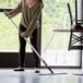 A woman using a Lavex blue microfiber mop to clean a floor.