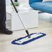 A person using a Lavex microfiber mop pad to clean a floor.