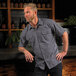 A man with a beard and mustache wearing a grey Mercer Culinary short sleeve work shirt.