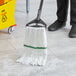 A person cleaning the floor with a white Lavex microfiber wet mop.