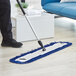 A person using a Lavex microfiber mop pad to clean a floor.