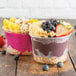 Two bowls of fruit and yogurt with toppings on a counter.