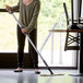 A woman using a Lavex aluminum spray mop handle to clean the floor.