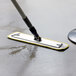 A yellow Lavex aluminum mop handle being used to clean a floor.