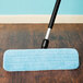 A Lavex blue microfiber mop pad attached to a black mop handle on a wood floor.