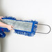 A person using a blue and grey Lavex dust mop pad on a mop handle.