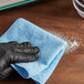A hand in a black glove wiping a blue cloth.