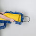 A woman using a Lavex yellow and blue microfiber dust mop pad on a mop.