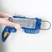 A person holding a blue and yellow Lavex microfiber dust mop pad.