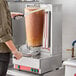 A man using an Avantco Electric Vertical Broiler to cut gyro meat.