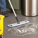 A person mopping the floor with a yellow Lavex 18" Microfiber Hook & Loop Wet / Dry Mop Frame.