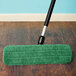 A Lavex green microfiber mop pad attached to a mop on a wood floor.