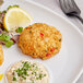 A plate with Crab House crab cakes and a side of lemon with green garnish.