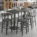 A Lancaster Table & Seating live edge bar height table with chairs around it.