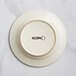 An ivory stoneware plate with an embossed wooden rim and the word Acopa on it.