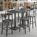A Lancaster Table & Seating live edge bar height table with chairs in a room.