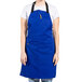 A woman wearing a royal blue Uncommon Chef bib apron.