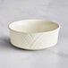 An Acopa ivory stoneware bowl with a wavy design on a table.