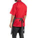 A man wearing a black and white striped butcher apron over a red shirt and black pants.