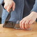 A hand using the Kai handheld knife sharpener to sharpen a knife.