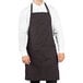 A man wearing a black and red pinstripe Uncommon Chef butcher apron.