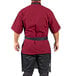 A man in a red shirt and black pants wearing a gray Uncommon Chef surge bib apron with black webbing.