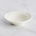An Acopa ivory stoneware bowl with an embossed wide rim on a marble surface.