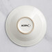 An ivory stoneware bowl with embossed circles and the word Acopa in black.