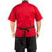 A man wearing a red shirt and a Uncommon Chef denim bib apron with black webbing.