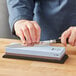 A person's hand using a Shun Combination Sharpening Stone to sharpen a knife.