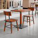 A rustic mahogany finish solid wood table with live edge and two matching industrial-style chairs.