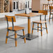 A honey maple finish solid wood table with a live edge and two matching industrial-style chairs.
