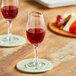 A close up of two Acopa Select sherry glasses filled with red liquid on a wooden table.