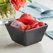 A matte black Acopa stoneware bouillon cup filled with fruit ice cream and grapes.