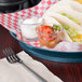 A table with a blueberry polypropylene round deli server filled with tacos and salsa.