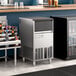 An undercounter stainless steel gourmet cube ice machine with a front panel and ventilation grilles.