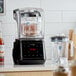 A commercial blender with a touchpad control panel, sound enclosure, and two clear blending jars.