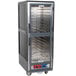 A large grey Metro C5 heated holding and proofing cabinet with clear Dutch doors and shelves.