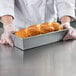 A person in gloves holding a loaf of bread in a Chicago Metallic bread loaf pan.